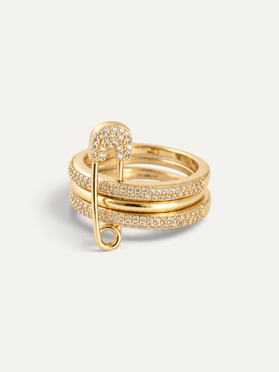 CÉLOIR Amara Ring aus goldfarbenem Edelstahl mit Sicherheitsnadel-Motiv und funkelnden Zirkonia-Steinen