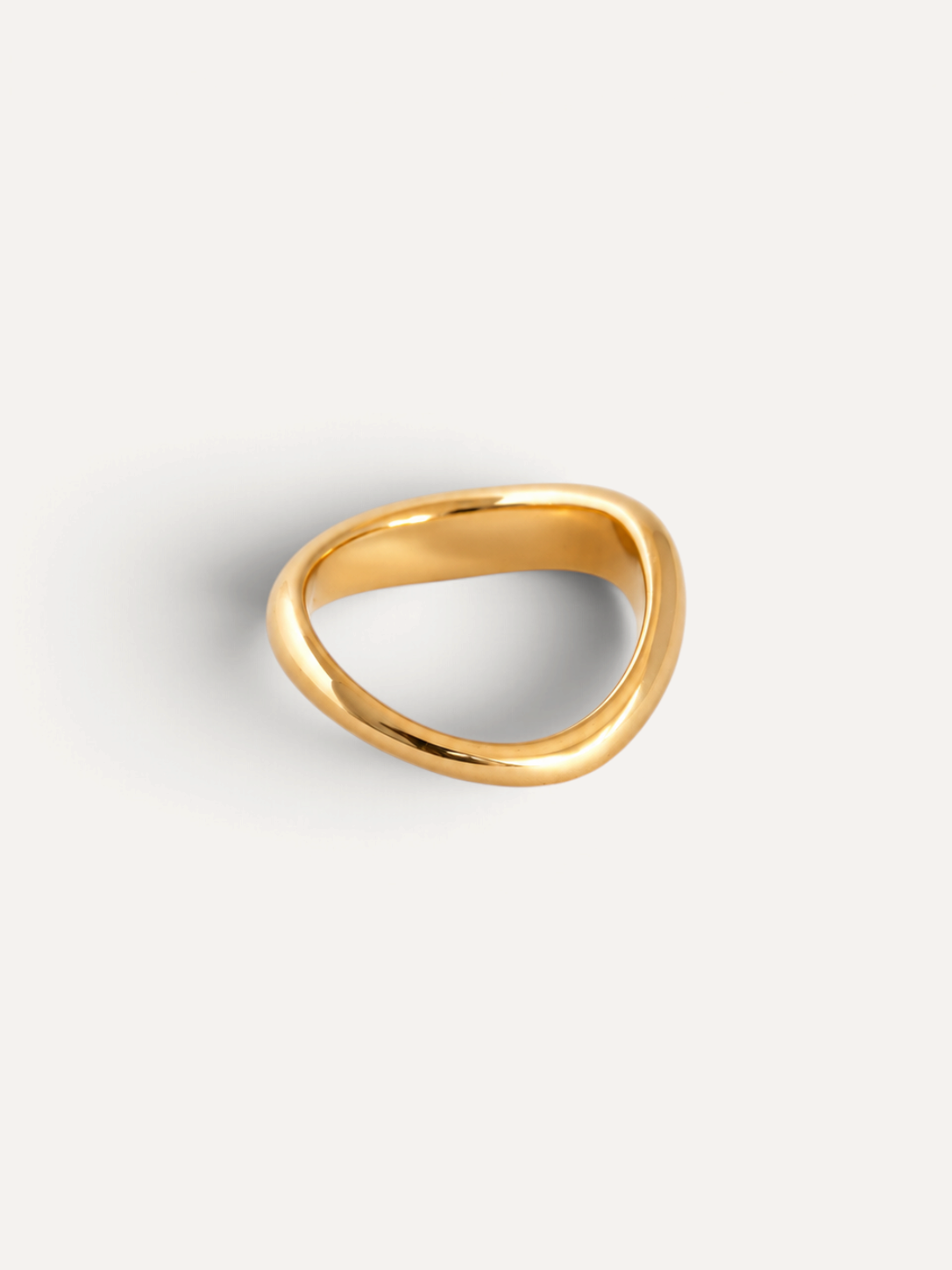 CÉLOIR VIONA Ring aus goldfarbenem Edelstahl mit organischer, geschwungener Form auf hellem Hintergrund