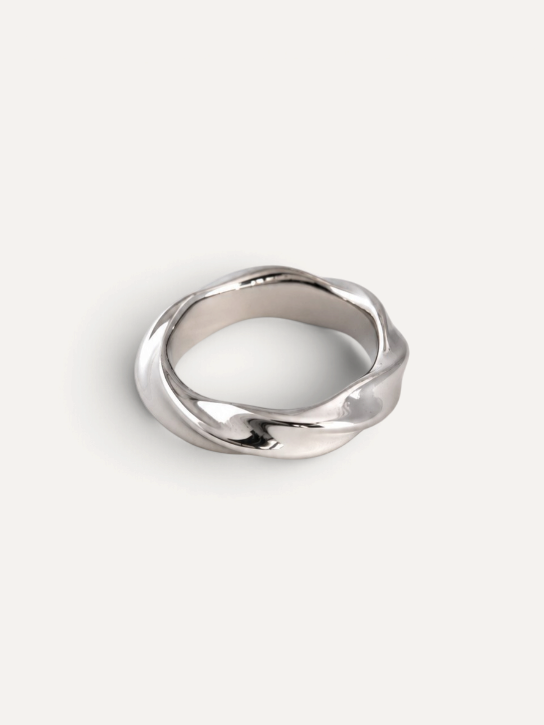 CÉLOIR Leya Ring aus silberfarbenem Edelstahl mit geschwungenem, gedrehtem Design auf hellem Hintergrund