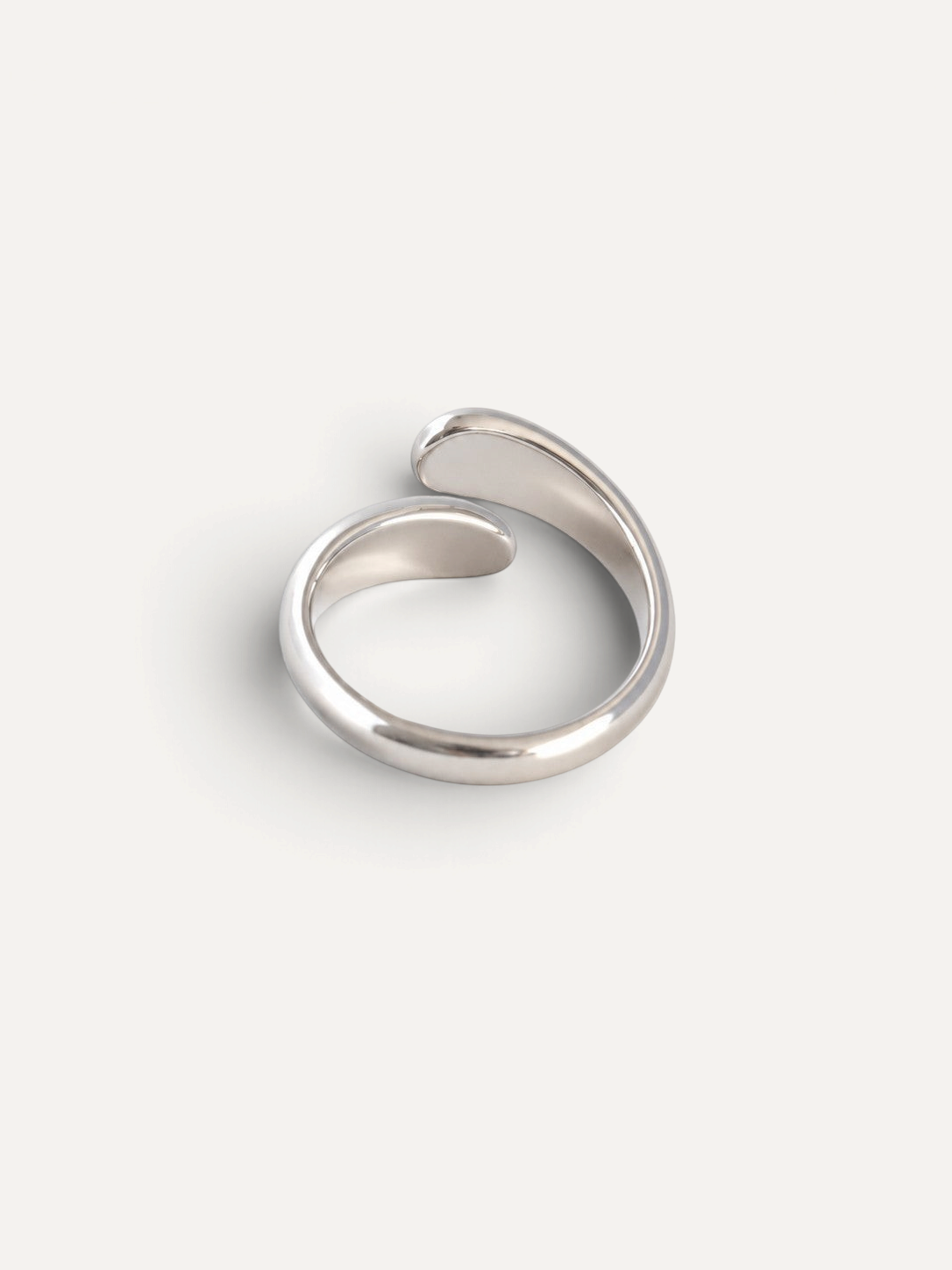 CÉLOIR Siena Ring aus silberfarbenem Edelstahl mit modernem, offenem Wickeldesign auf weißem Hintergrund