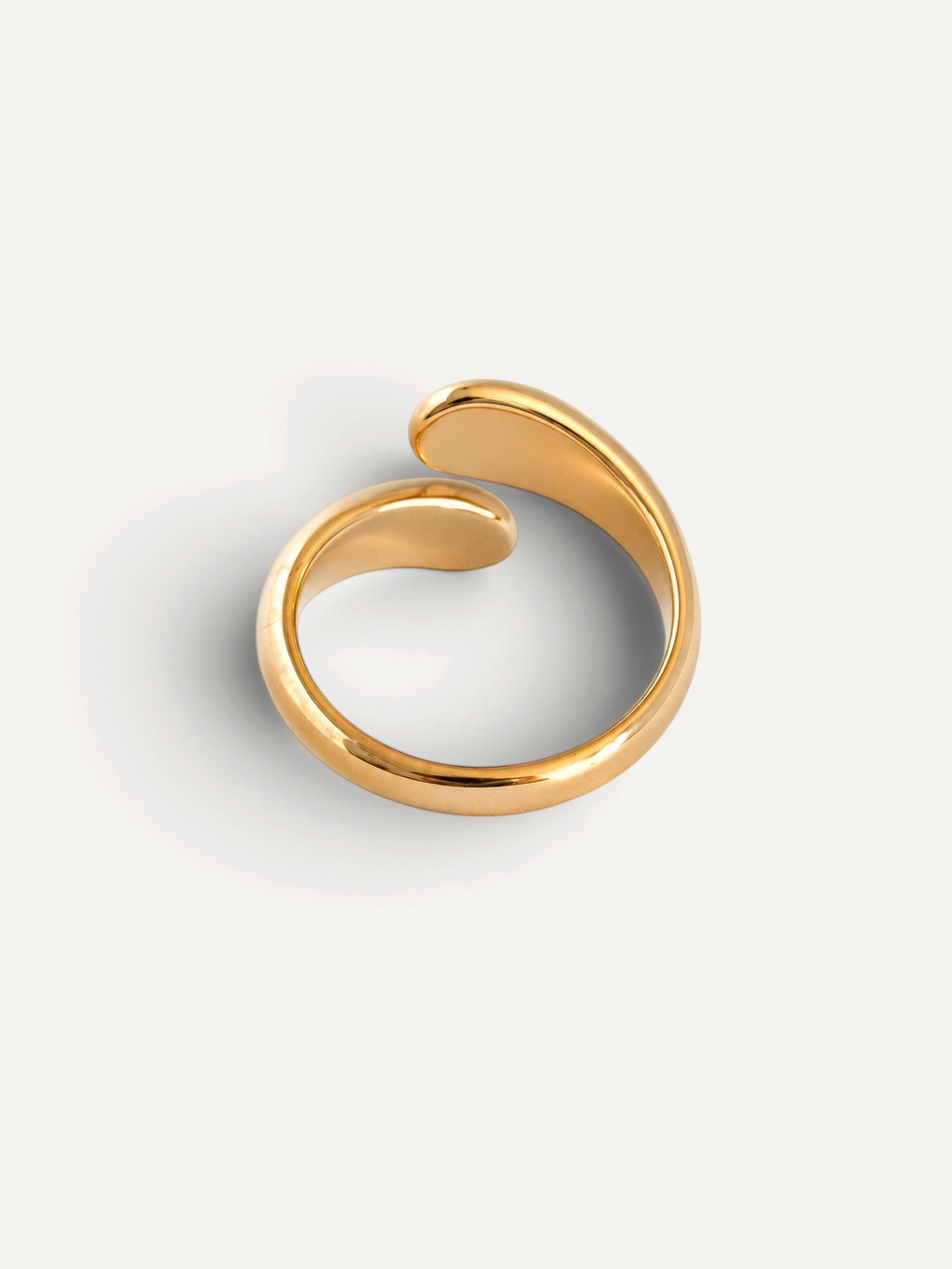 CÉLOIR Siena Ring aus goldfarbenem Edelstahl mit modernem, offenem Wickeldesign auf weißem Hintergrund