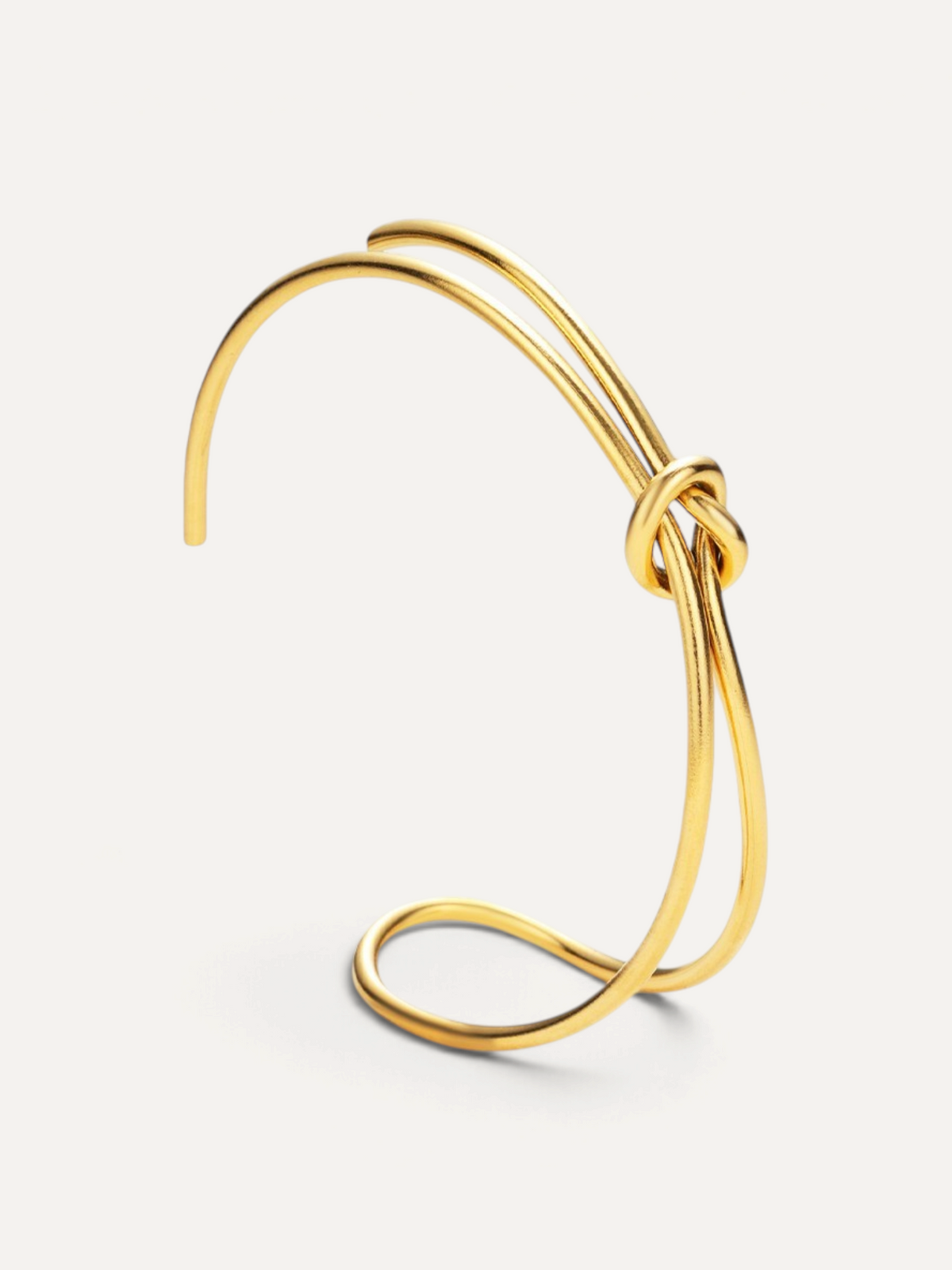 CÉLOIR TIED Armreif aus goldfarbenem Edelstahl mit elegantem Knotendesign in offener Form