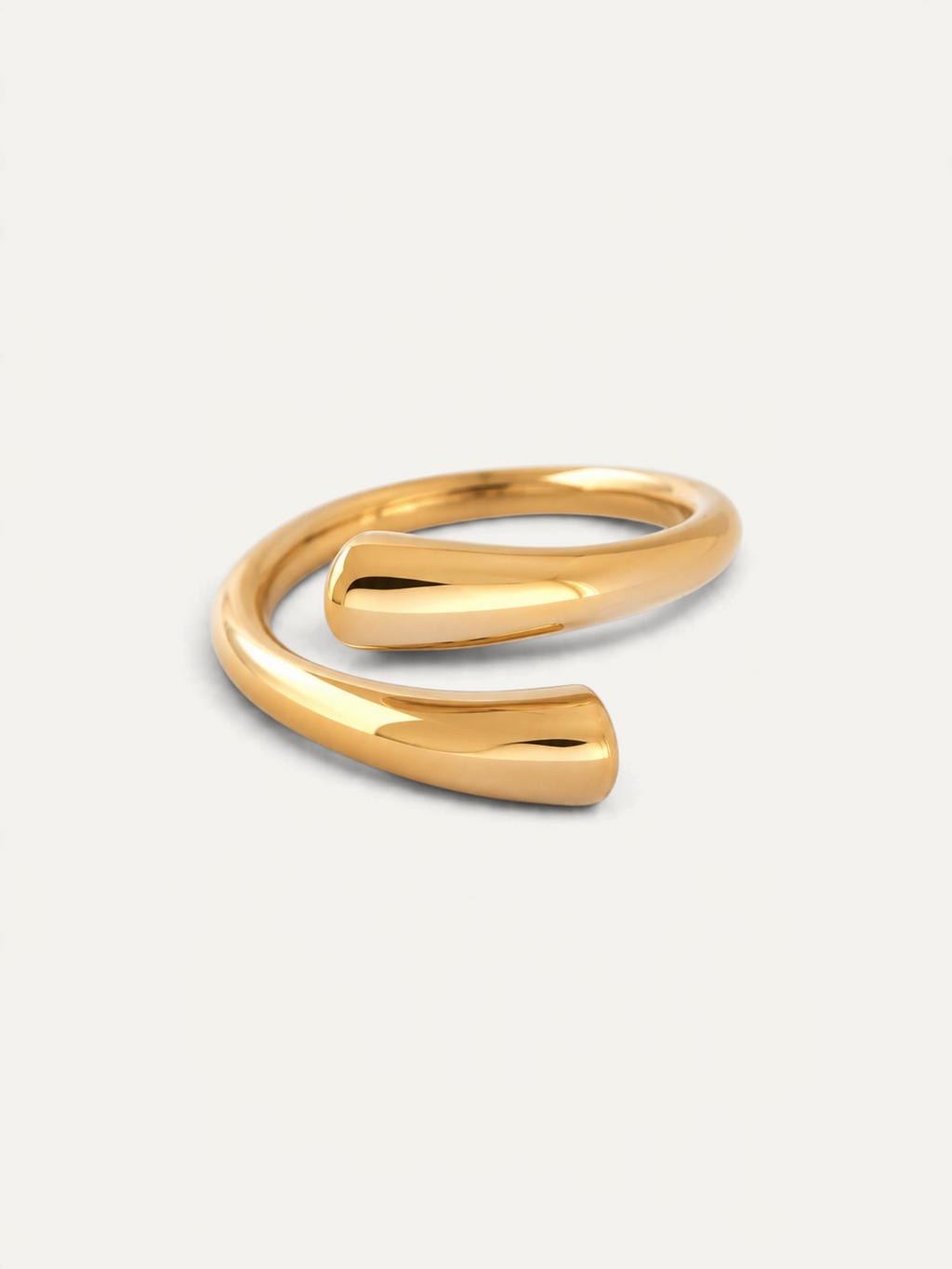 CÉLOIR TWIN RING aus goldfarbenem Edelstahl in modernem, offenem Wickeldesign auf weißem Hintergrund