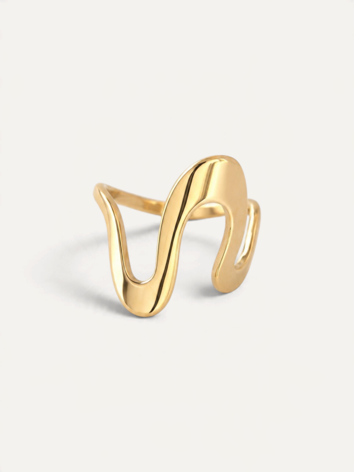 CÉLOIR Vantage Ring aus goldfarbenem Edelstahl mit geschwungenem, wellenförmigem Design auf weißem Hintergrund