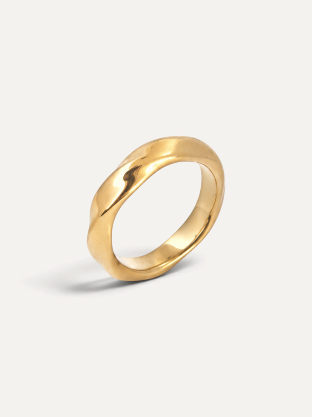 CÉLOIR Leya Ring aus goldfarbenem Edelstahl mit organischer, gewellter Oberfläche auf weißem Hintergrund